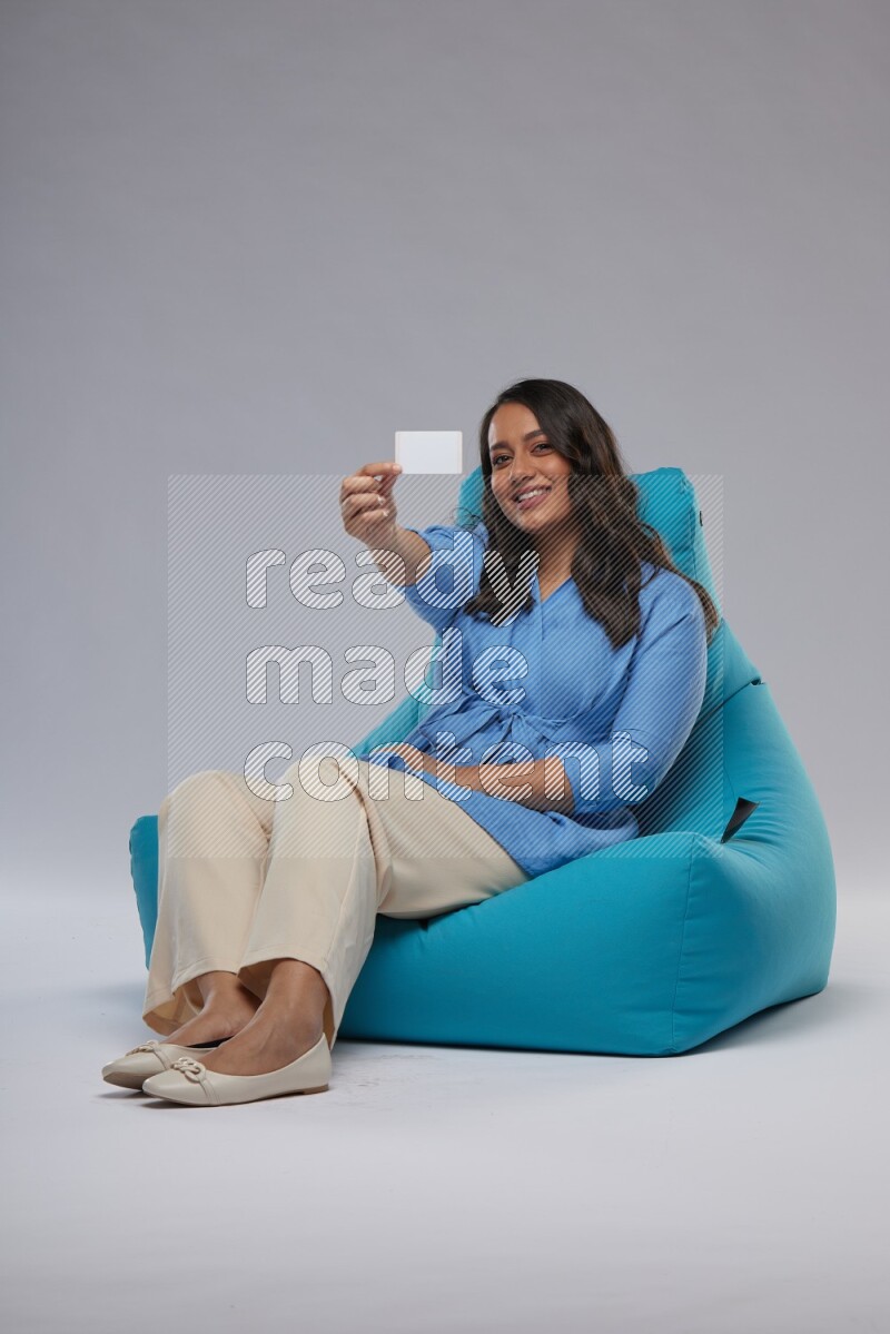 A woman sitting on a blue beanbag and holding ATM card