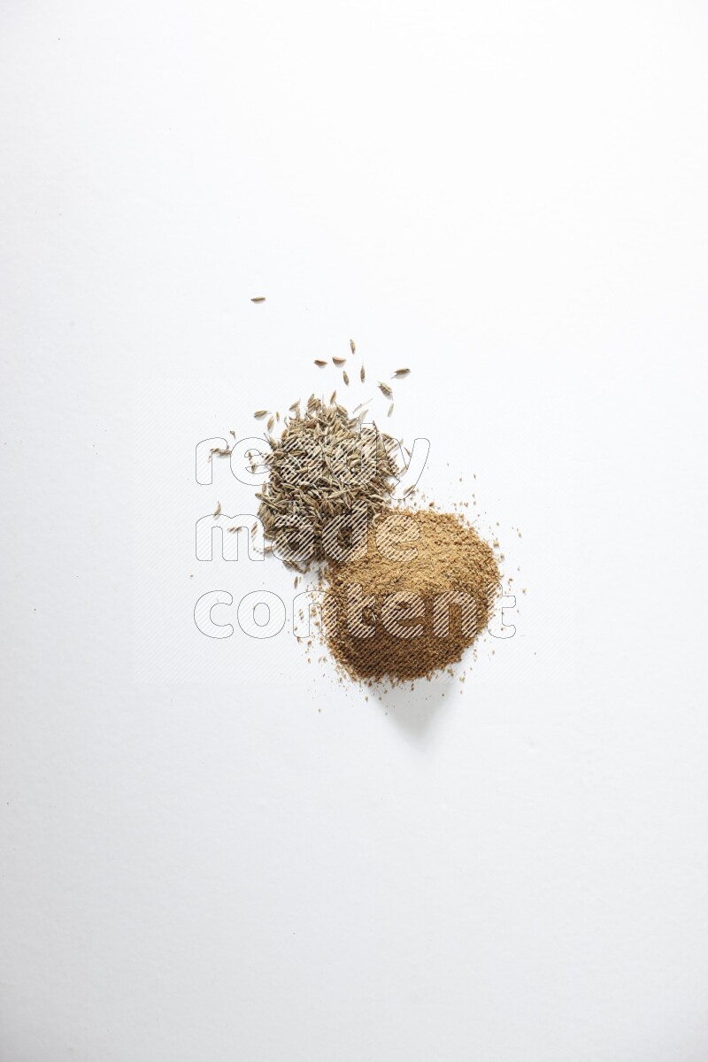 Cumin seeds and cumin powder on white flooring