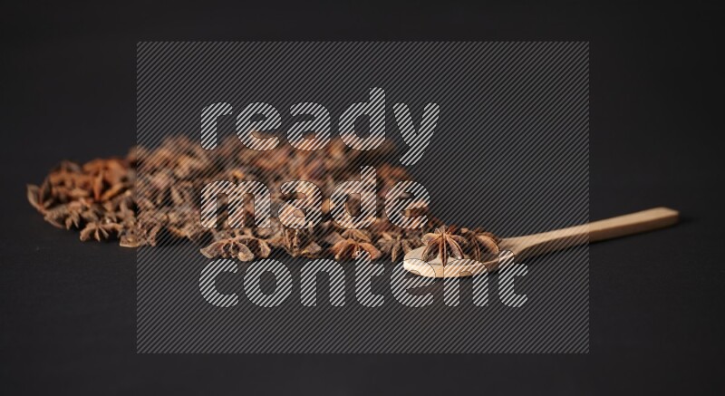 Star Anise in a wooden spoon and spreading on a black flooring