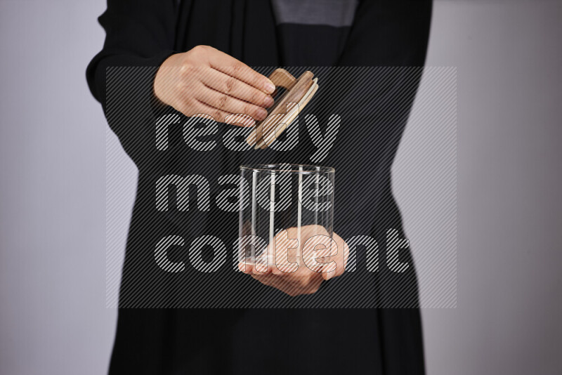 A woman in black abaya holding different glassware in different positions