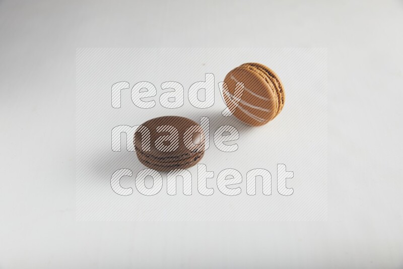 45º Shot of of two assorted Brown Irish Cream, and Brown Dark Chocolate macarons on white background