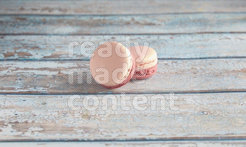 45º Shot of two Pink Litchi Raspberry macarons on light blue wooden background