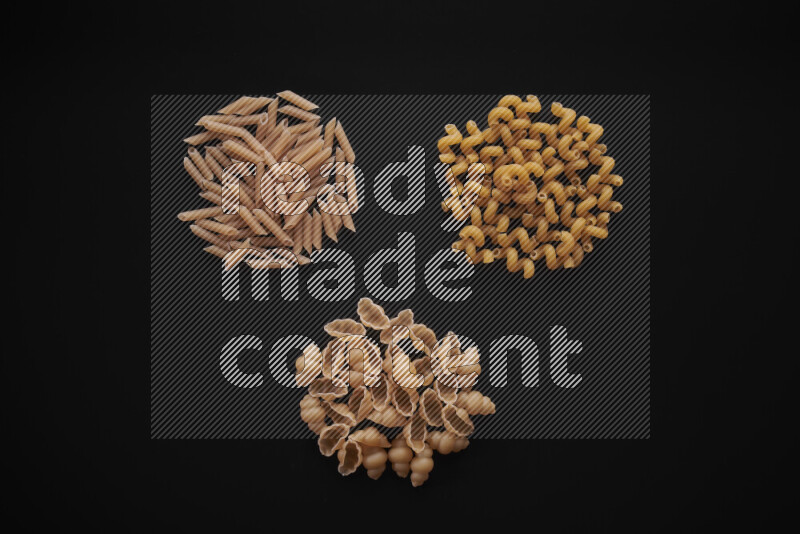 Different pasta types in bunches on black background