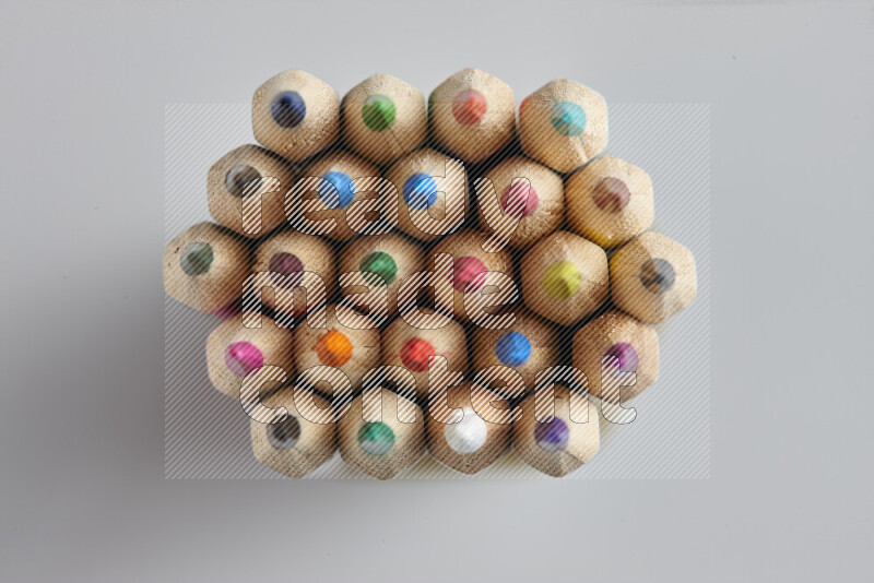 The image captures top view shot of sharpened colored pencils on grey background