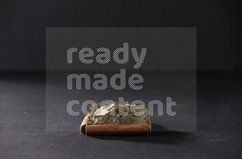 A single square of cinnamon sticks full of laurel bay on black flooring