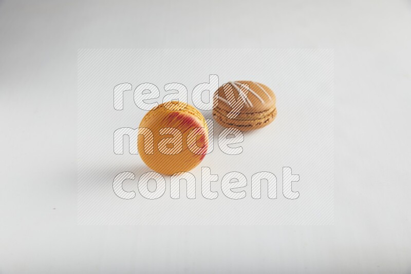 45º Shot of of two assorted Brown Irish Cream, and Orange Exotic macarons on white background