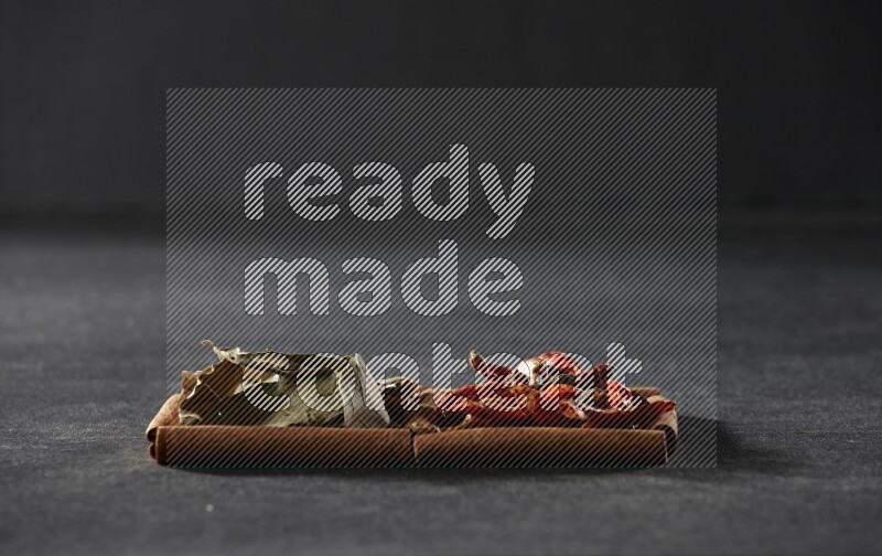 2 squares of cinnamon sticks full of chilis and bay laurel leaves on black flooring