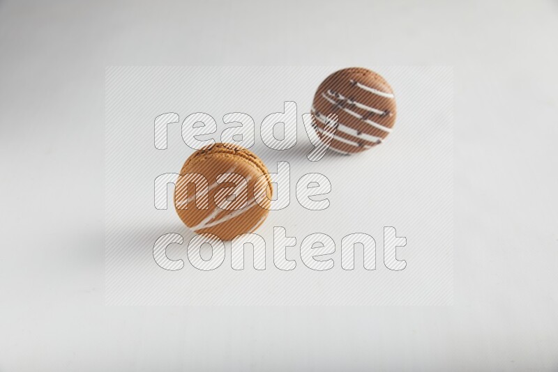 45º Shot of of two assorted Brown Irish Cream, and Brown white Chocolate Caramel macarons on white background