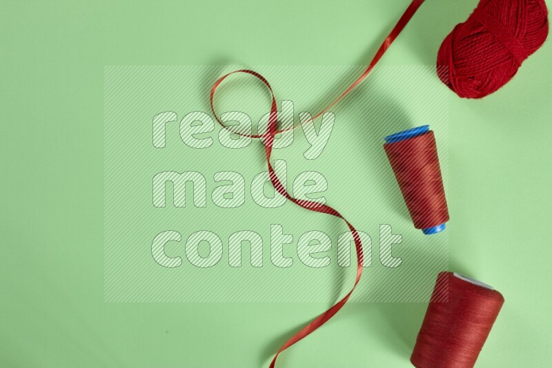 A red collection of sewing and tailoring tools arranged on a green background
