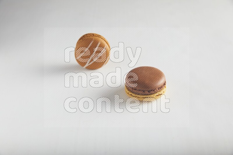 45º Shot of of two assorted Brown Irish Cream, and Yellow, and Brown Chai Latte macarons on white background