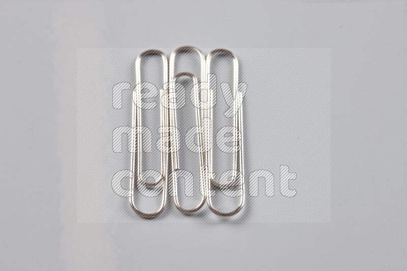 Silver paper clips isolated on a grey background