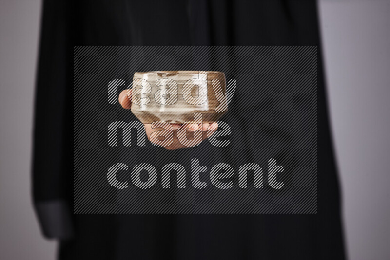 A woman in black abaya holding different pottery essentials in different positions