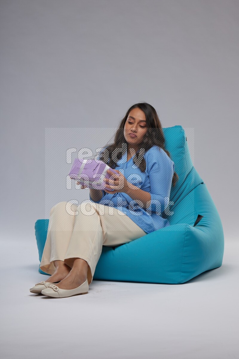 A woman sitting on a blue beanbag and holding a gift