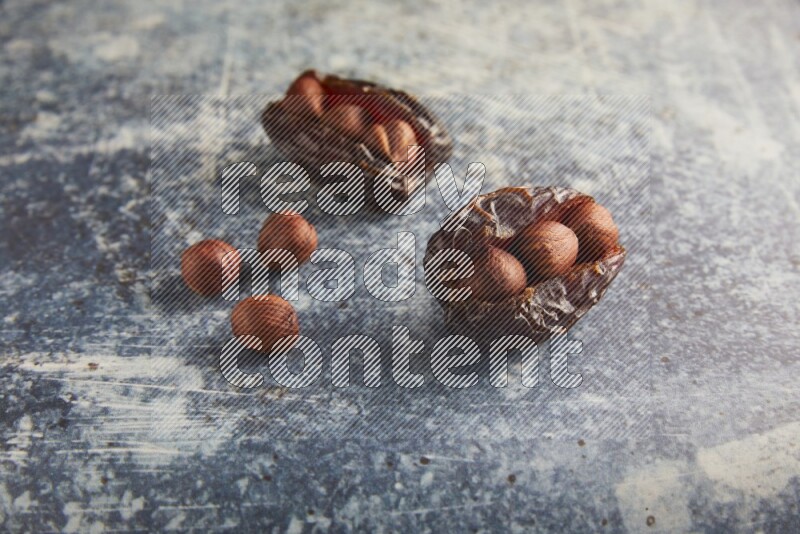 two hazelnuts stuffed madjoul dates on a rustic blue background