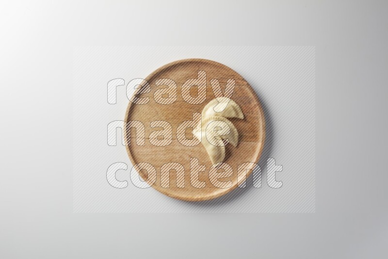 Three Sambosas on a wooden round plate on a white background