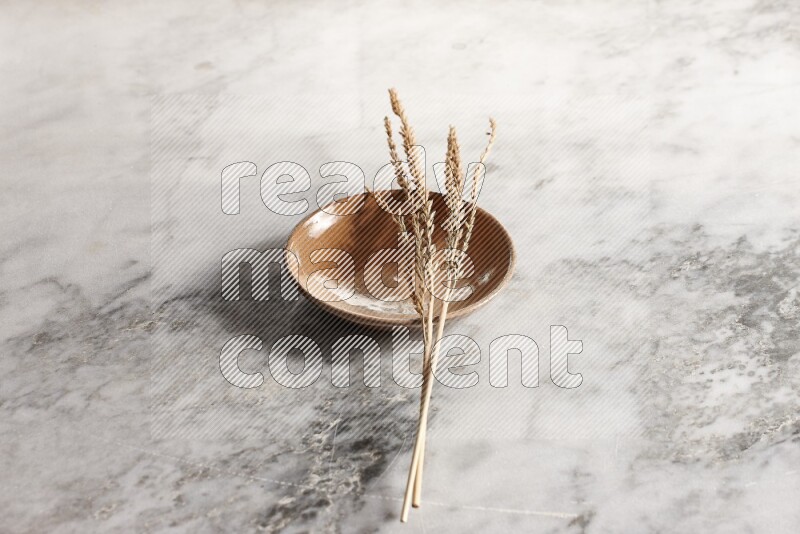 Wheat stalks on multicolored pottery plate on grey marble background