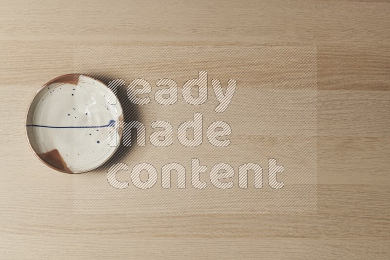 صحن فخاري متعدد الألوان على خلفية خشبية فاتحة