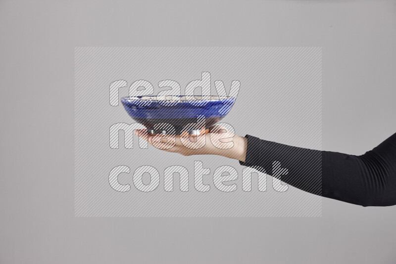 A woman in black abaya holding different pottery essentials in different positions