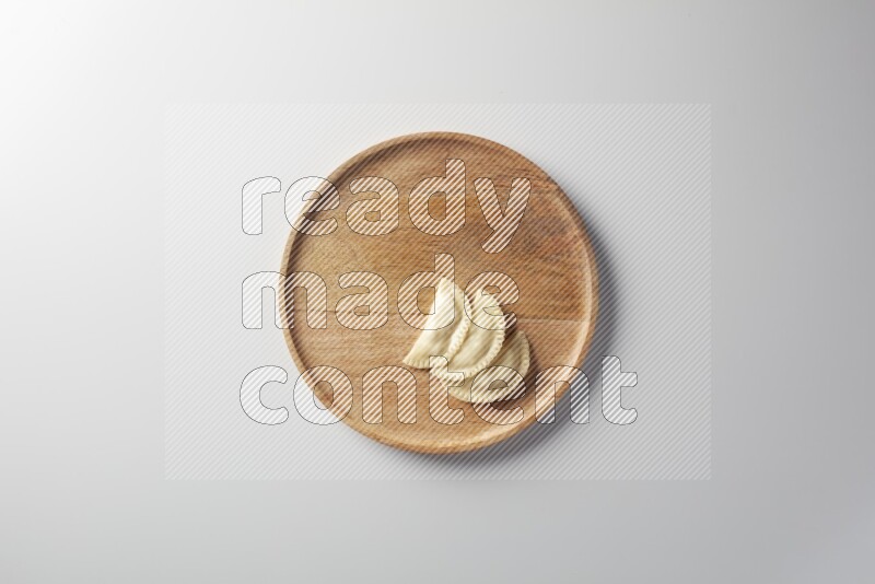 Three Sambosas on a wooden round plate on a white background