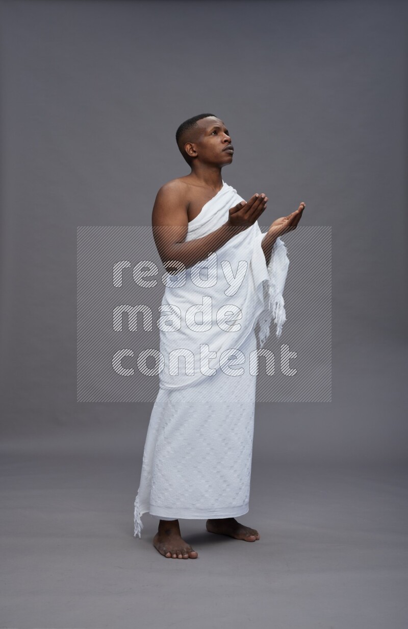 A man wearing Ehram Standing dua'a on gray background