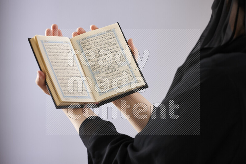 A woman hands holding moshaf in different positions