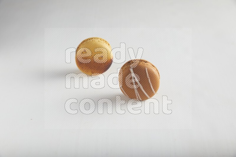 45º Shot of of two assorted Brown Irish Cream, and Yellow Crème Brulée macarons on white background