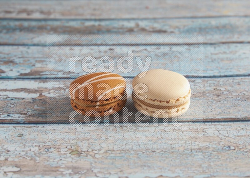 45º Shot of of two assorted Brown Irish Cream, and White Caramel fleur de sel macarons on light blue background