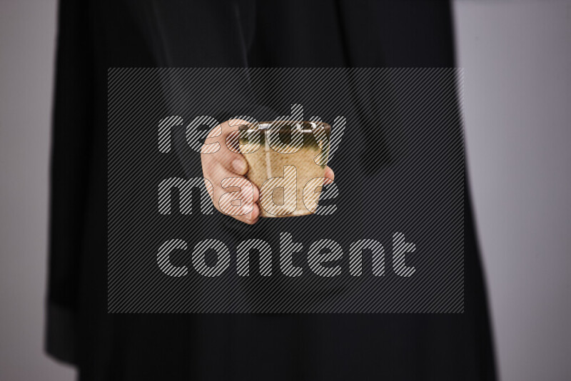 A woman in black abaya holding different pottery essentials in different positions