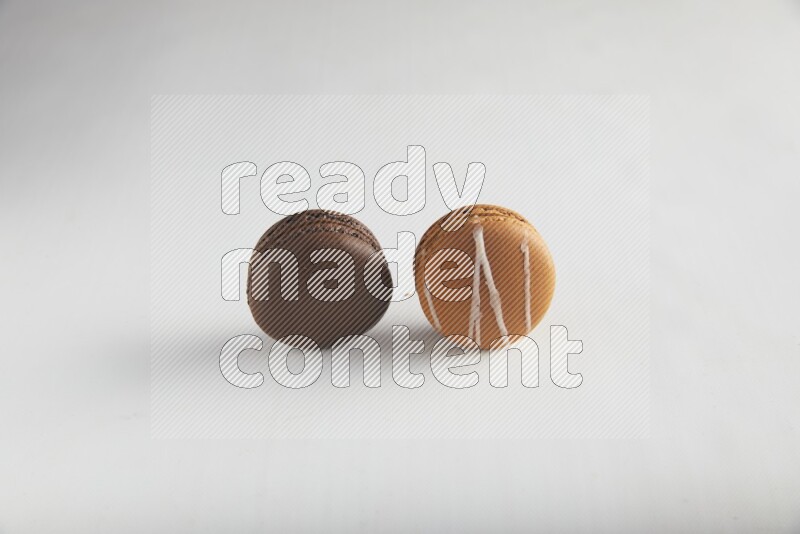 45º Shot of of two assorted Brown Irish Cream, and Brown Dark Chocolate macarons on white background