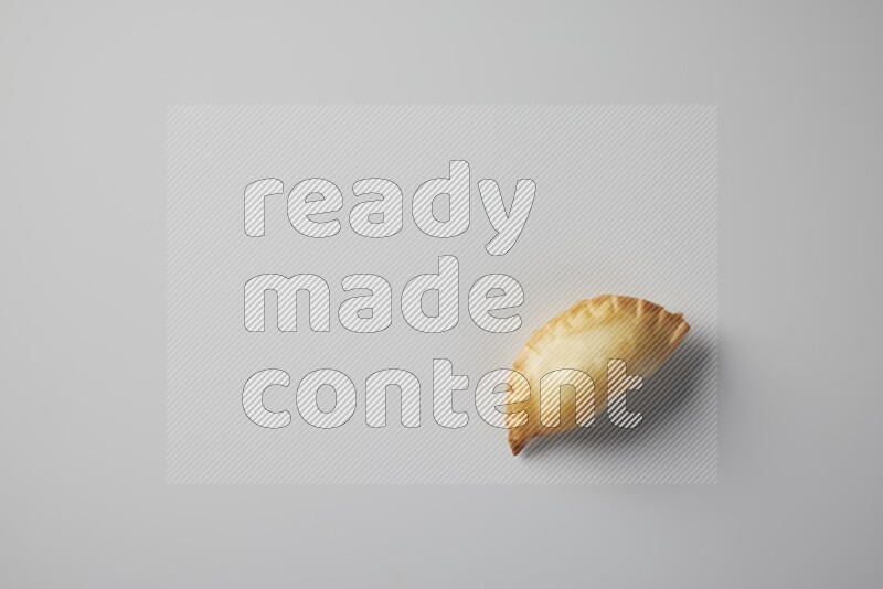 One fried sambosa from a top angle on a white background