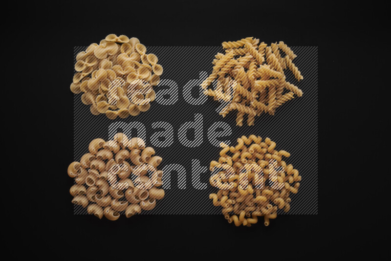 Different pasta types in bunches on black background