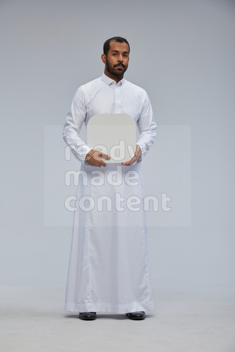 Saudi man wearing Thob standing holding social media sign on Gray background
