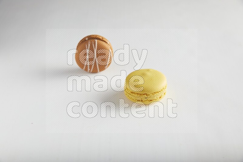 45º Shot of of two assorted Brown Irish Cream, and Yellow Lemon macarons on white background