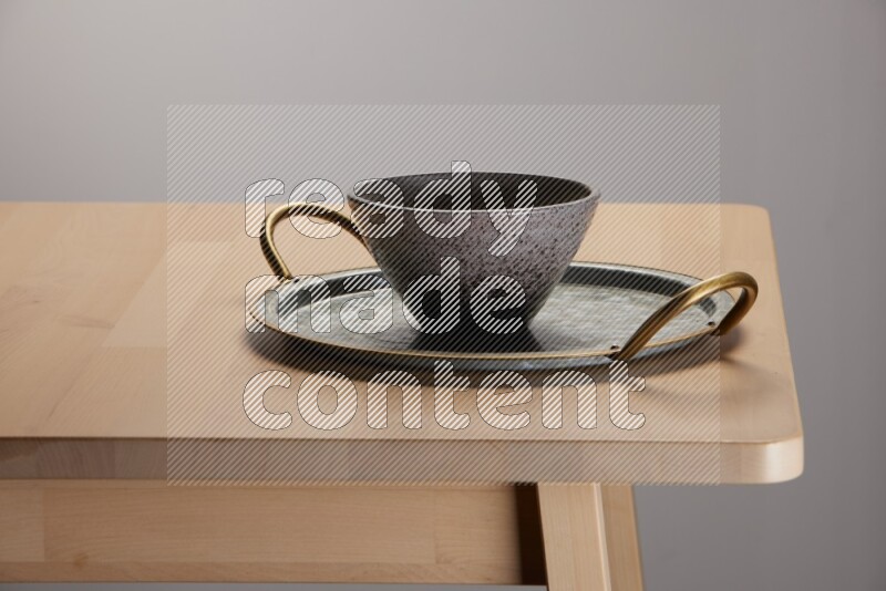 multicolored bowl placed on a rounded stainless steel tray with golden handels on the edge of wooden table