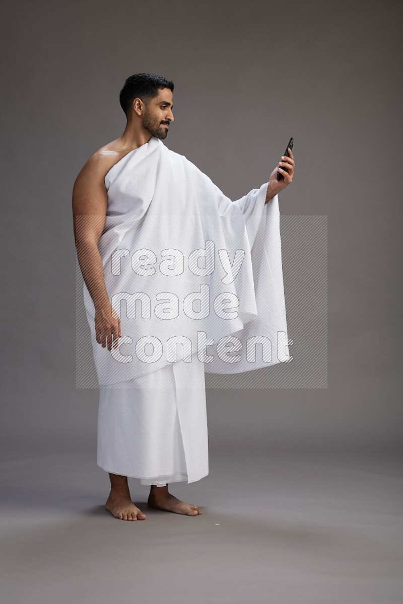 A man wearing Ehram Standing taking selfie on gray background