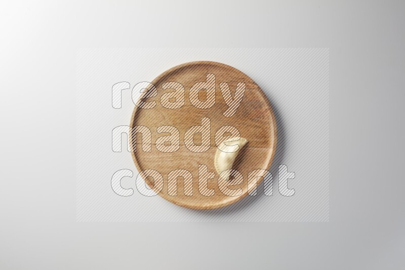 A single Sambosa on a wooden round plate on a white background