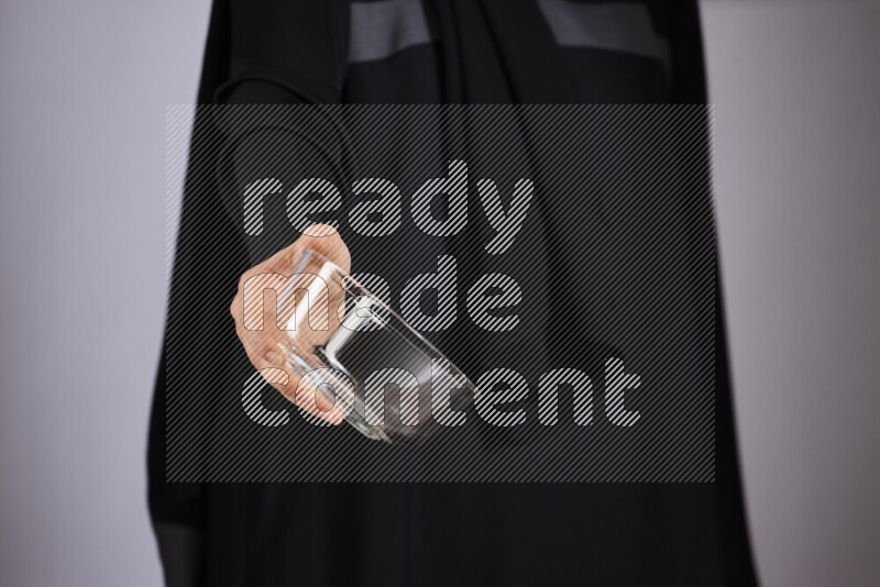 A woman in black abaya holding different glassware in different positions