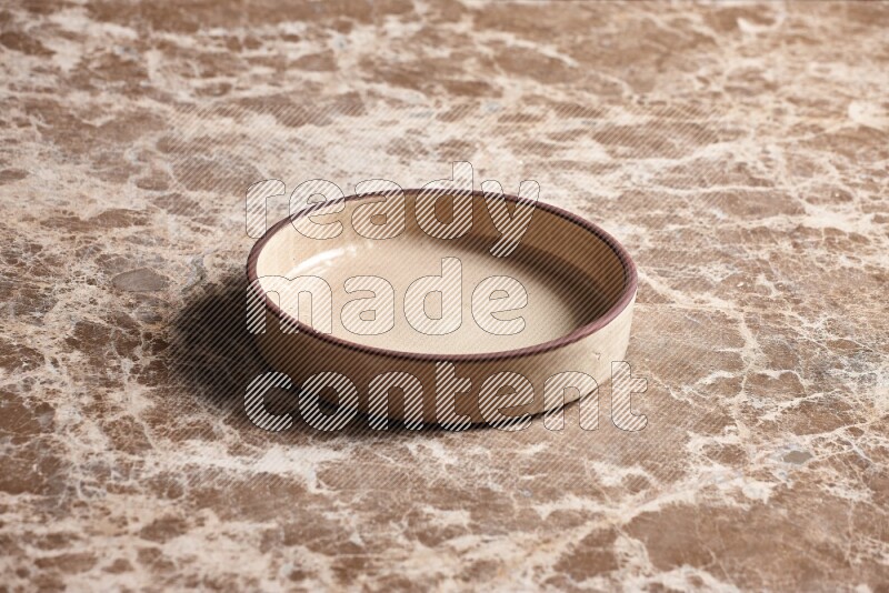 A beige pottery oven plate on beige marble background
