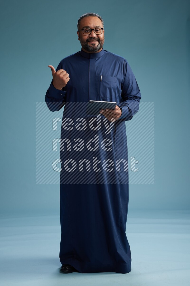 Saudi Man without shimag Standing working on tablet on blue background