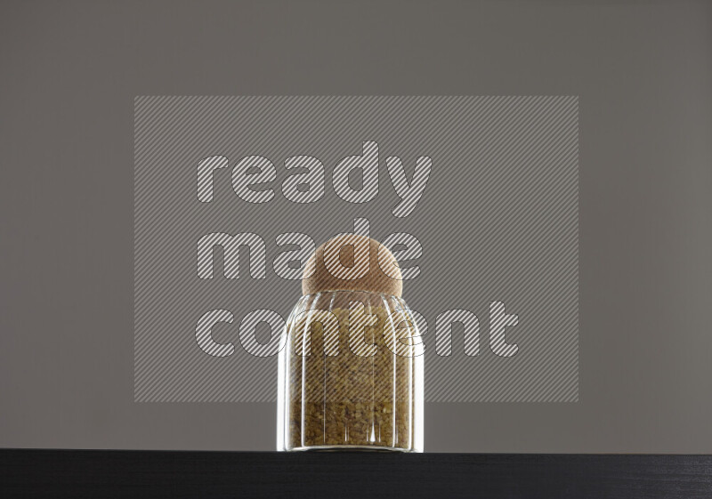 Coarse bulgur in a glass jar on black background