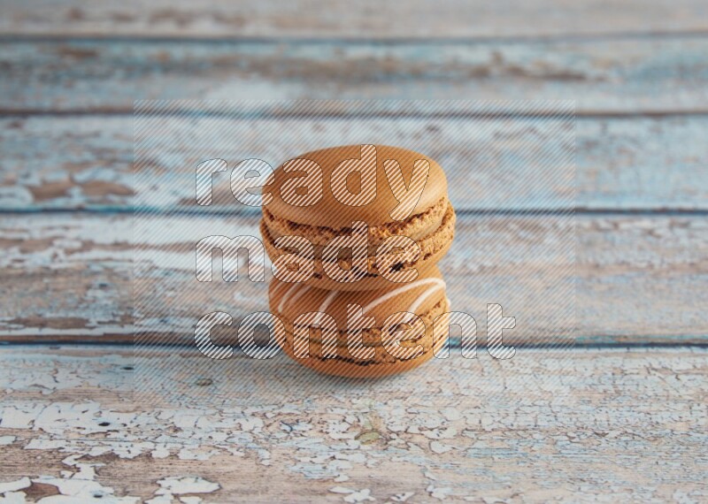 45º Shot of of two assorted Brown Irish Cream, and Brown Maple Taffy macarons  on light blue background