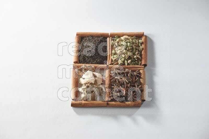 4 squares of cinnamon sticks full of tea, cardamom, star anise and ginger on white flooring