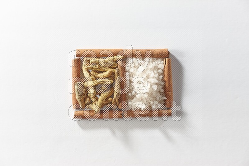 2 squares of cinnamon sticks full of turmeric fingers and white salt on white flooring