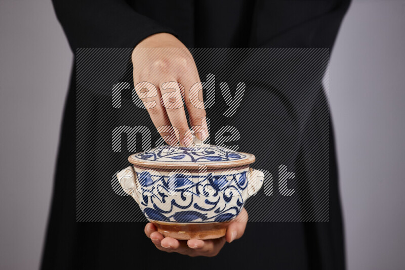A woman in black abaya holding different pottery essentials in different positions
