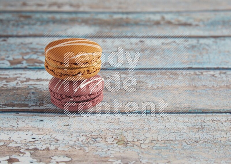 45º Shot of of two assorted Brown Irish Cream, and Red Poppy Flower macarons  on light blue background
