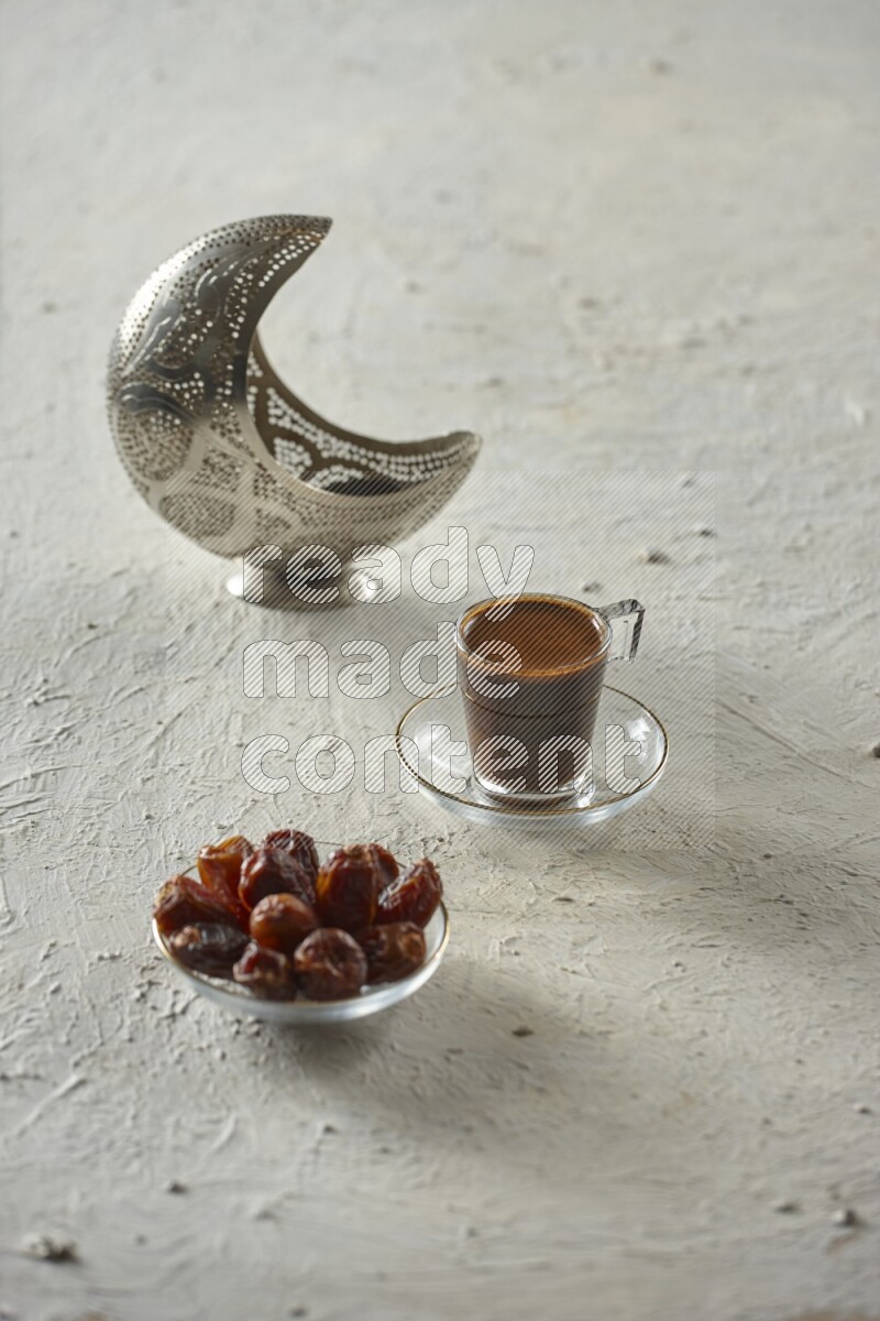 A silver lantern with different drinks, dates, nuts, prayer beads and quran on textured white background