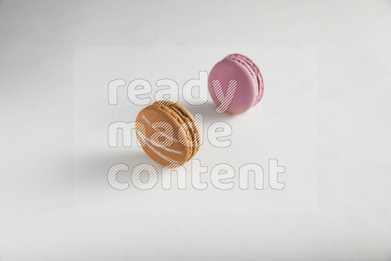 45º Shot of of two assorted Brown Irish Cream, and Purple Strawberry macarons on white background