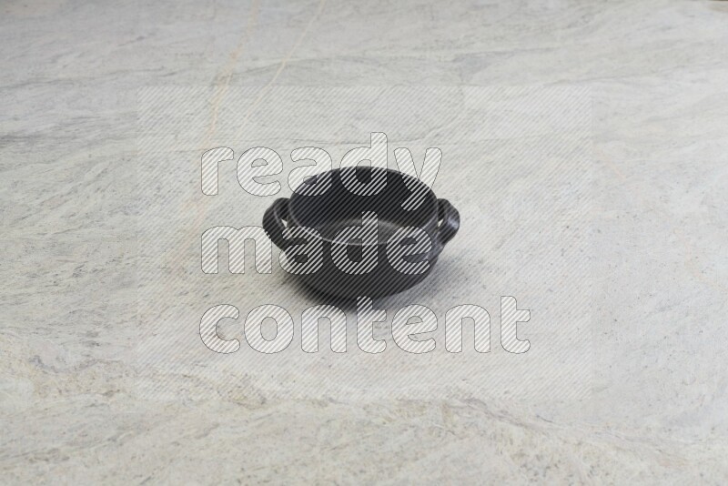 A black pottery bowl on grey marble background