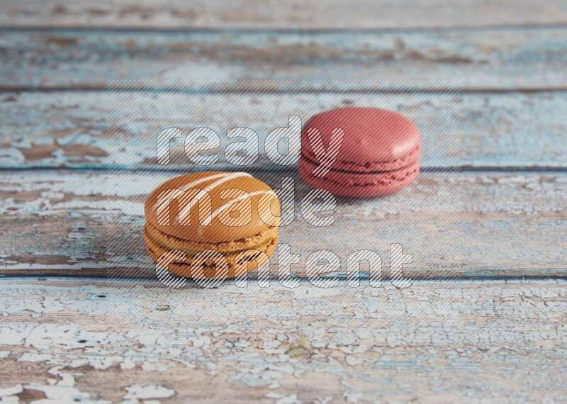 45º Shot of of two assorted Brown Irish Cream, and Pink Raspberry macarons on light blue background
