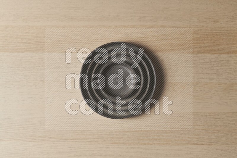 A pottery black ripple plate on light wooden background